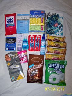 the contents of a diaper bag laid out on a white sheet with some snacks