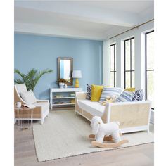 a living room with blue walls, white furniture and yellow accents on the rugs