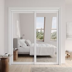 a white bed sitting inside of a bedroom next to a window