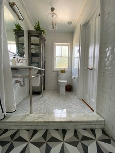 a white bathroom with black and white tile flooring