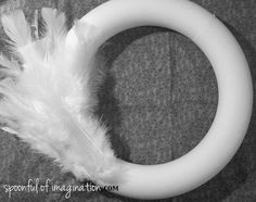 a white ring with feathers on it sitting on top of a gray cloth covered floor