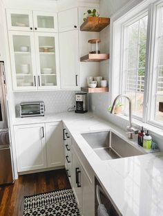 a kitchen with white cabinets and black and white area rugs on the hardwood floor