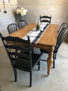 a wooden table with black chairs and a checkered table cloth on it, in front of a wood paneled wall