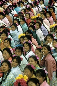 a large group of people standing next to each other with flowers in their hair and wearing headbands