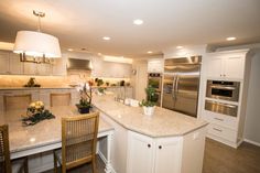 a large kitchen with an island in the middle and two chairs at the counter top