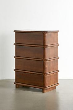 a wooden dresser sitting on top of a floor next to a white wall in an empty room