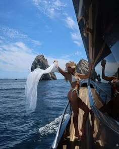 two women in bikinis on the deck of a boat with veil flying over them