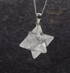 a star shaped glass pendant on a silver chain with a black stone surface in the background