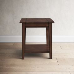 a small wooden table sitting on top of a hard wood floor next to a white wall