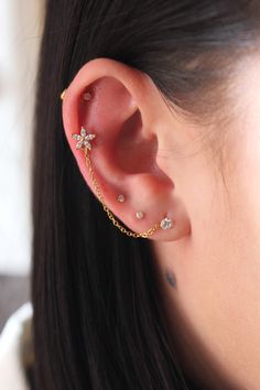 a woman wearing an ear piercing with three small stars on the side of her ear