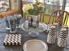 the table is set with black and white plates, napkins, vases and glasses