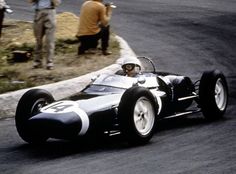 a man driving a race car down a road with people watching from the sidelines