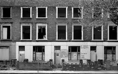 a black and white photo of an old building with boarded up windows on the side