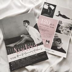 two magazine covers sitting on top of a bed covered in white sheets and black and white photos