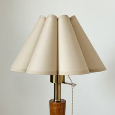 a wooden table lamp with a beige shade on it's base and chain hanging off the side