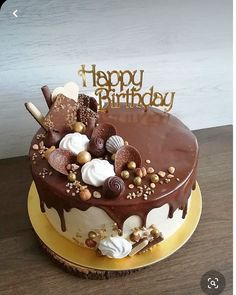 a birthday cake with chocolate icing and nuts on top, sitting on a table