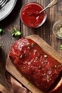 a wooden cutting board topped with meat covered in marinara sauce