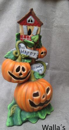 two pumpkins sitting on top of each other near a house with happy written on it