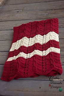 a red and white knitted blanket laying on top of a wooden floor next to a bottle