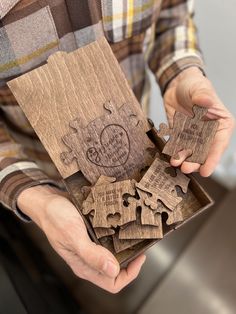 a person holding a wooden puzzle in their hands with the pieces missing from it,