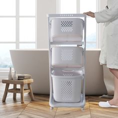 a woman standing next to a bath tub with three baskets on the bottom and one in the middle