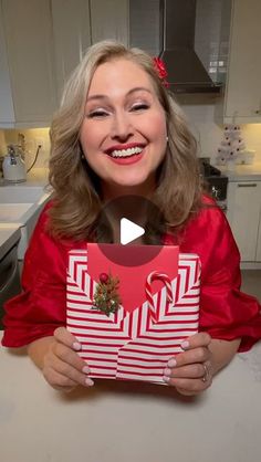 a woman is holding up a christmas present