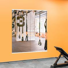 there is a gym with exercise equipment on the wall and an orange wall behind it