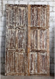 two old wooden doors are shown against a brick wall