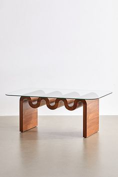 a glass and wood coffee table with wavy lines on the top, in front of a white wall