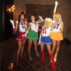 three women dressed in costumes posing for the camera with one holding up her hand and two wearing short skirts