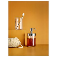 a soap dispenser, brush and towel on a yellow surface with an orange wall in the background