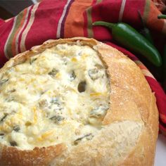 a close up of a bread with cheese and meat in it on a towel next to peppers