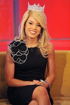 a woman wearing a tiara sitting on a couch with a smile on her face