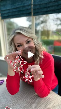 a woman is holding up some candy canes to her face while sitting at a table