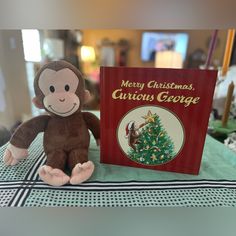 a stuffed monkey sitting next to a christmas book