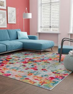 a living room with pink walls, blue couches and colorful rug on the floor