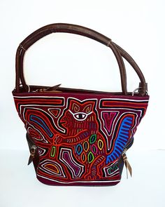 "A brown leather shoulder bag with an exquisite and original hand-sewn Mola decoration on the front.  Each Mola design and textile is 100% unique and 100% handmade by Indigenous Kuna woman. Fashionable, timeless, and practical, a perfect bag for any occasion. Features: - Zippered main compartment for safety - Two inset pockets for mobile/tissues - One interior zippered pocket for money/cards/keys - Two zippered outer side pockets Dimensions: W 34cm x H 28cm x D 14cm - Handle drop 21cm Fabric: Ma Traditional Brown Shoulder Bag For Everyday Use, Brown Embroidered Satchel For Travel, Embroidered Brown Hobo Tote Bag, Embroidered Brown Tote Hobo Bag, Embroidered Brown Hobo Shoulder Bag, Embroidered Brown Hobo Bag, Brown Hand Tooled Tote Shoulder Bag, Brown Hand Tooled Shoulder Bag For Travel, Brown Embroidered Hobo Shoulder Bag