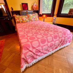 a bed with pink and white bedspread sitting on top of a hard wood floor