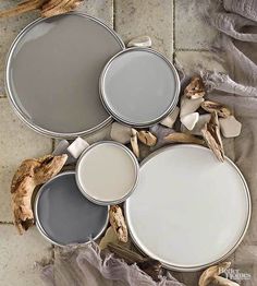 three paint cans sitting on top of a tile floor next to dried up driftwood