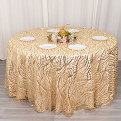 the table is set with three white plates and two champagne glasses on top of it