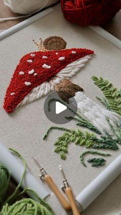 a close up of a piece of art on a table with crochet needles