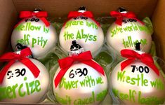 six glass christmas ornaments in a box with red bows on the top and green lettering