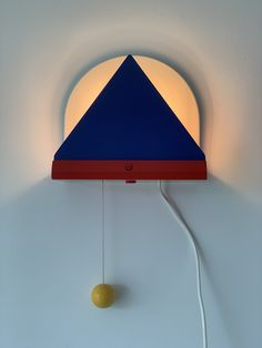 a blue and red lamp hanging from the side of a wall next to a yellow ball