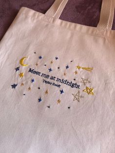 A captivating tote bag featuring golden stars and the phrase 'Meet Me at Midnight' inspired by Taylor Swift, perfect for dreamers and romantics.✨💫 Totebag Embroidery Idea, Cute Merch Ideas, Tote Bag Design Embroidery, Embroidery On Tote Bags, Taylor Swift Embroidery Ideas, Embroidery Tote Bag Design, Tote Bag Diy Design, Tote Bag Embroidery Ideas, Starry Night Crochet