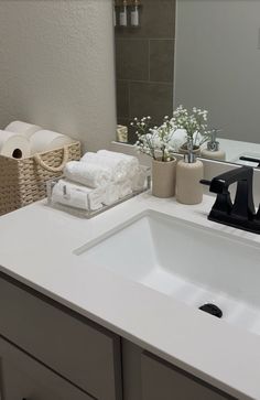 a white bathroom sink sitting under a mirror next to a toilet paper dispenser