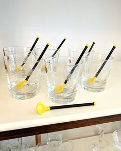 several glasses with black and yellow handles are lined up on a table