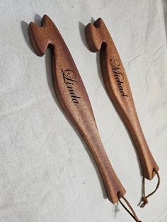 two wooden spoons with names on them sitting on a white cloth covered tablecloth