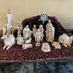 the nativity scene is on display in front of an ornate red cloth covered table