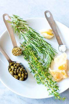 a white plate topped with olives and bread next to utensils on top of a table