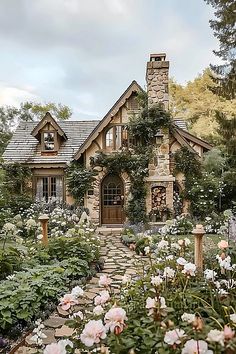 a stone house surrounded by flowers and greenery